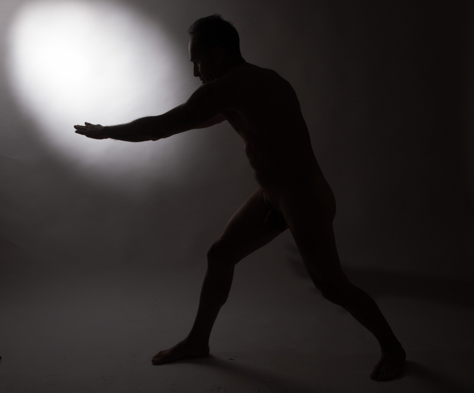 Silueta en blanco y negro de una figura humana en movimiento frente a una fuente de luz